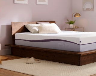 An unmade Purple Plus mattress in a bedroom