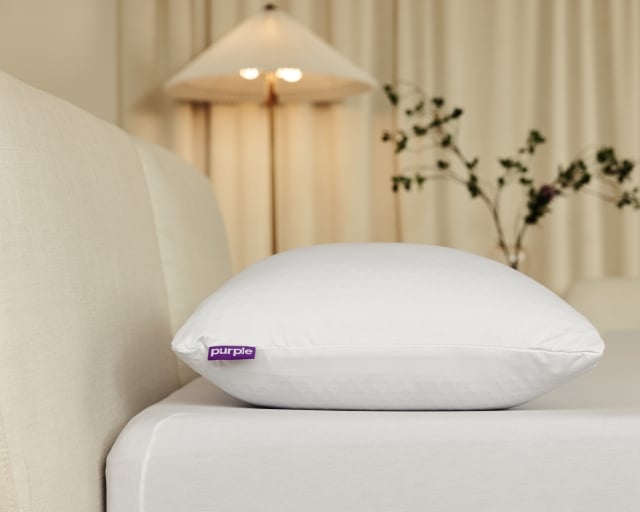 A Purple Harmony pillow in a minimalist bedroom.