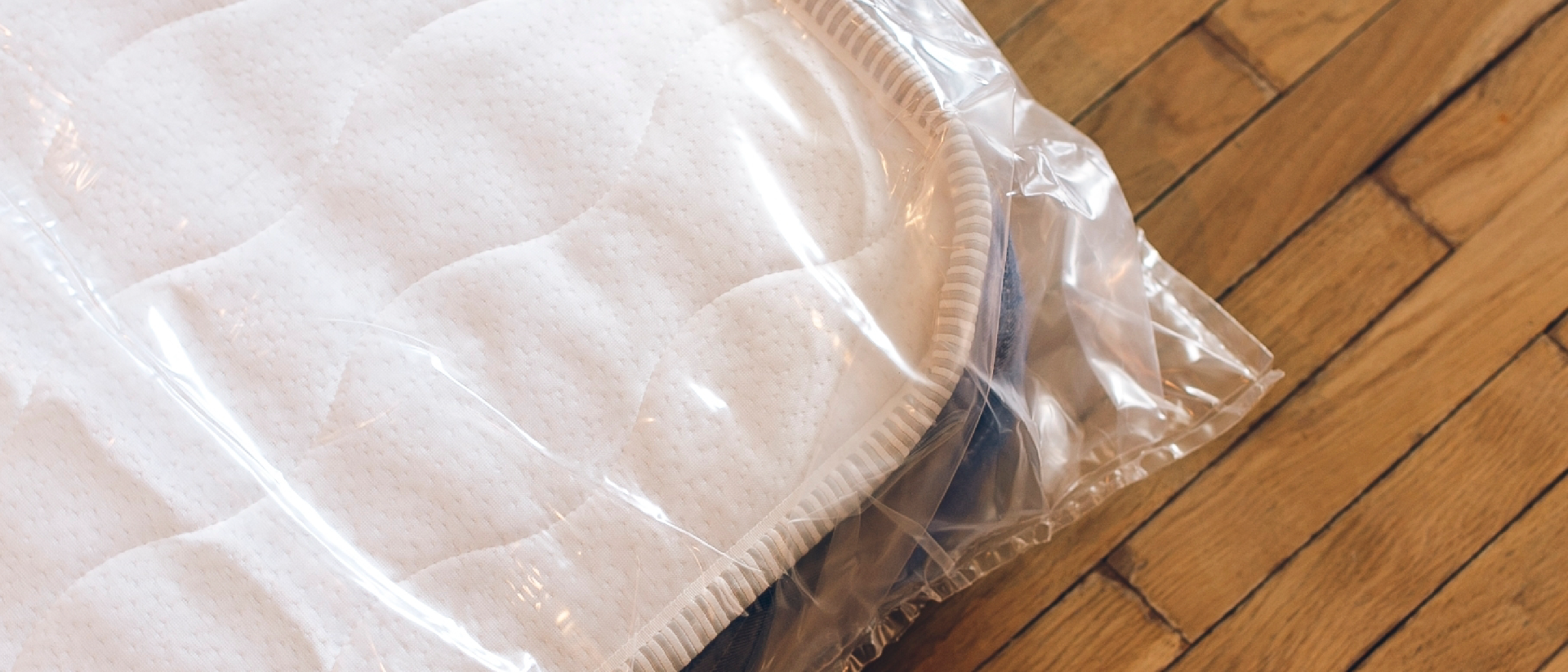 A mattress wrapped in plastic lying flat for storage.